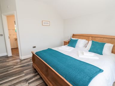 A bedroom with a wooden bed frame blue pillows and a blue throw next to a nightstand at Deanrise in Shilbottle near Alnwick