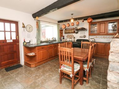 A kitchen with wooden cabinets and a wooden dining table with chairs at Harbour Cottage in Watchet
