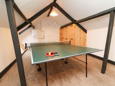 A loft room with a ping pong table and wooden cabinets at Harbour Cottage in Watchet