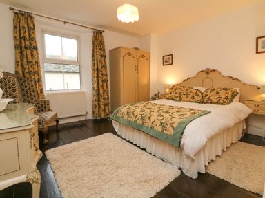 A bedroom with a double bed lamps on bedside tables and an armchair at Harbour Cottage in Watchet