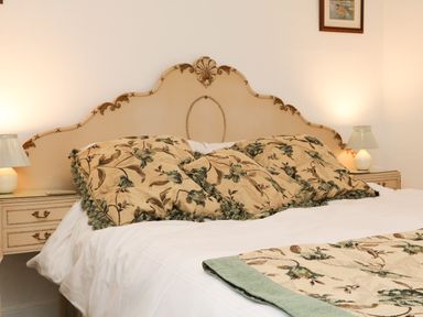 A bedroom with a bed with floral pillows and a matching runner and bedside tables with lamps at Harbour Cottage in Watchet