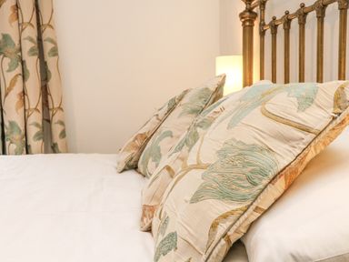 A bed with patterned pillows and matching curtains at Harbour Cottage in Watchet