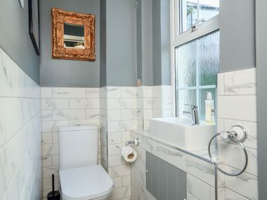 A bathroom with a toilet, sink, mirror, and window at Ferrystone Kingswear near Dartmouth