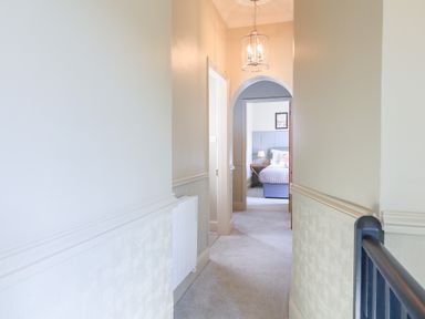 A hallway with light fixture leading to a bedroom with a bed and lamp at Ferrystone Kingswear near Dartmouth
