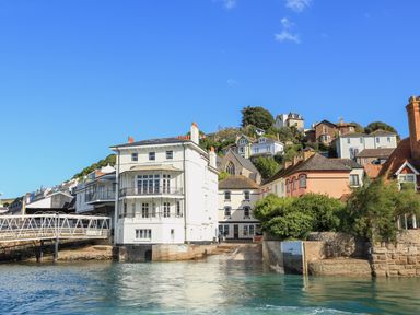A waterfront view of buildings and houses on a hillside with a clear blue sky at Ferrystone Kingswear near Dartmouth