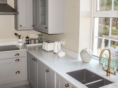 A kitchen countertop with a toaster kettle utensils and a sink near a window at Ferrystone in Kingswear near Dartmouth