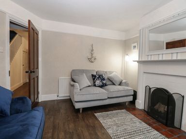 A living room with two sofas a fireplace and a rug at Hunny Cottage in Hunstanton