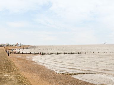 A beach with a stone wall on the left and wooden groynes extending into the sea at Hunny Cottage in Hunstanton