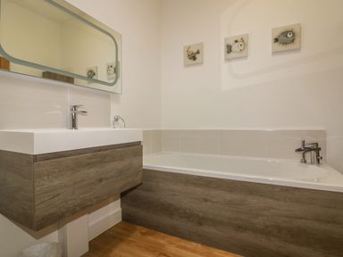 A bathroom with a bathtub and a sink with a wooden cabinet at Woodhall in Cardinham