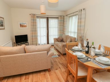 A living room with two beige sofas and a wooden dining table set for four at 2 Chandlers Yard in Burry Port
