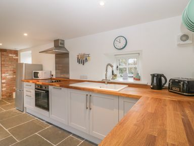 A kitchen with wooden countertops a sink stove oven microwave refrigerator kettle toaster and knives on a wall at Magnolia Barn in Mark