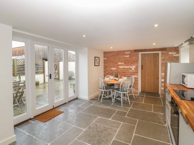 A kitchen with a dining table set for four near a brick wall and glass doors leading outside at Magnolia Barn in Mark