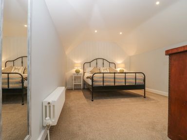 A bedroom with a black metal bed frame pillows bedside tables with lamps a radiator and a wooden chest of drawers at Magnolia Barn in Mark