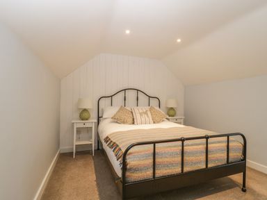 A bedroom with a double bed a metal frame two bedside tables with lamps at Magnolia Barn in Mark