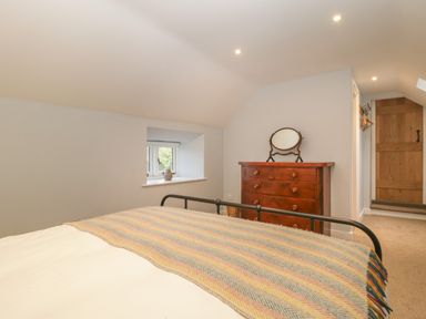 A bedroom with a bed a chest of drawers with a mirror and a window with a vase at Magnolia Barn Mark