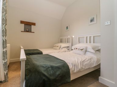A bedroom with two single beds with white bedding and green blankets at Magnolia Barn in Mark
