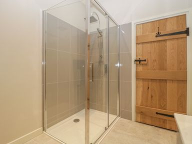 A bathroom with a glass shower enclosure and wooden door at Magnolia Barn in Mark