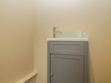 A small bathroom sink with a gray cabinet and a chrome faucet against a beige wall at Magnolia Barn in Mark