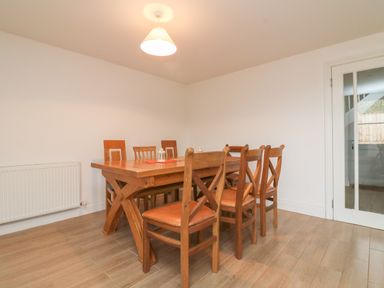 A dining room with wooden chairs and table with a hanging light and radiator at The Outlook in Crowcombe