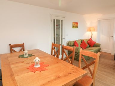 A dining area with wooden table and chairs and a sitting area with green sofa and red cushions at The Outlook in Crowcombe