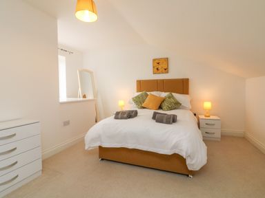 A bedroom with a double bed with cushions and towels bedside tables with lamps a dresser and a standing mirror at The Outlook in Crowcombe