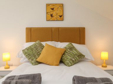 A bed with yellow and green pillows and two bedside tables with yellow lamps at The Outlook in Crowcombe