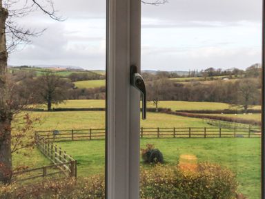 A countryside view through a window showing fields trees and fences at The Outlook in Crowcombe