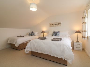 A bedroom with two beds each with cushions and towels with nightstands and lamps at The Outlook in Crowcombe