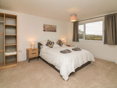 A bedroom with a double bed two bedside tables lamps and a window with curtains at The Outlook in Crowcombe
