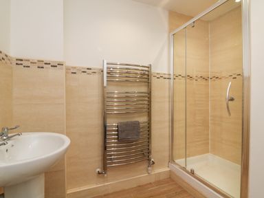 A bathroom with a sink a towel heater with a towel and a glass shower enclosure at The Outlook in Crowcombe