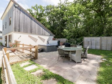 An outdoor patio area with a round glass table and chairs next to a modern two-story building at The Outlook in Crowcombe