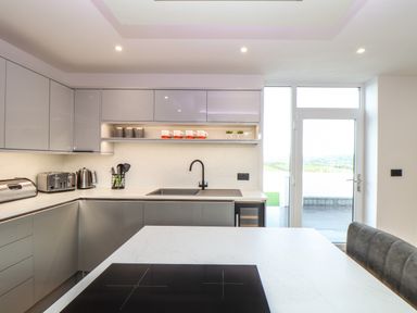 A modern kitchen with white countertops grey cabinets a black sink toaster kettle and induction stove at Valley View in Mullion