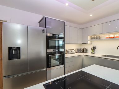 A modern kitchen with stainless steel refrigerator ovens toaster kettle and utensils at Valley View in Mullion
