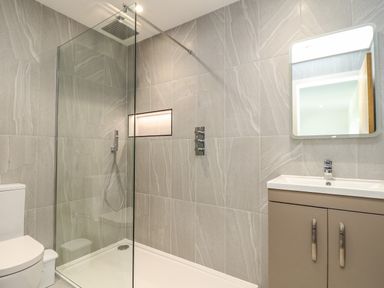 A bathroom with a glass shower enclosure toilet and a vanity with a mirror at Valley View in Mullion