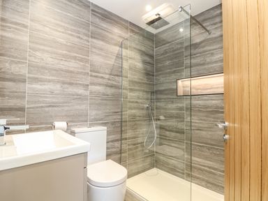 A bathroom with a shower area enclosed by glass a toilet and a sink with a faucet at Valley View in Mullion