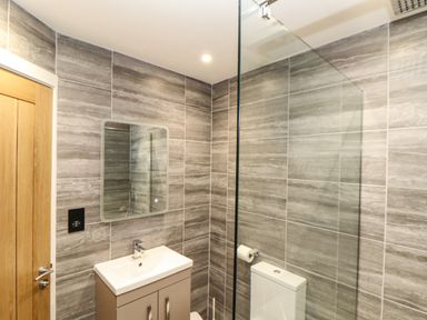 A bathroom with a sink cabinet mirror toilet and glass shower screen at Valley View in Mullion