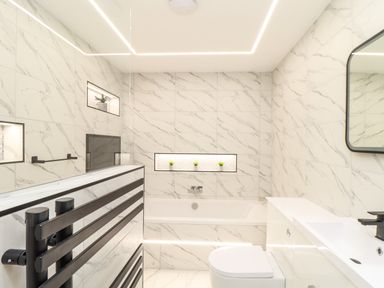 A bathroom with a bathtub small potted plants on wall niches a toilet sink and mirror at Valley View in Mullion