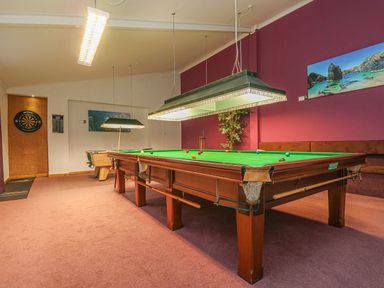 A game room with a snooker table, a pool table, two hanging lights, a dartboard, and pictures on the wall at Valley View in Mullion