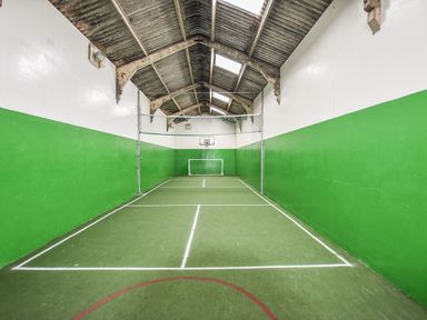 An indoor sports court with green walls white lines a basketball hoop and a small soccer goal at Valley View in Mullion