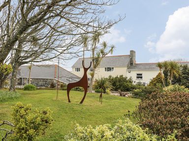 A garden with metal animal sculptures trees and bushes in front of a house at Valley View in Mullion