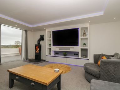 A living room with a wall-mounted TV a stove and a wooden coffee table at Valley View in Mullion