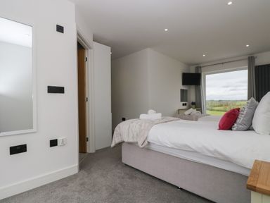 A bedroom with a large bed pillows and window showing a rural view at Valley View in Mullion