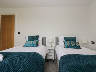 A bedroom with two single beds a white nightstand and lamps at Valley View in Mullion