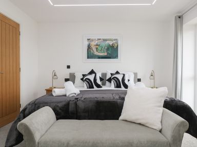 A bedroom with a bed pillows lamps and a bench in front at Valley View in Mullion