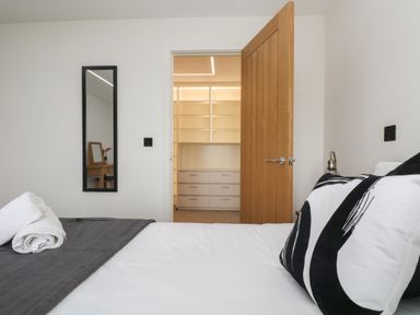 A bedroom with a bed pillows and towels next to a wooden door leading to a closet with shelves at Valley View in Mullion