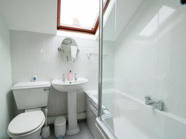 A bathroom with a toilet sink mirror bathtub and skylight at Tawny Cottage in Heacham