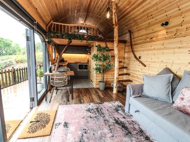 An interior wooden cabin with a kitchen area loft dining table chairs sofa and staircase at Offas Dyke Escape in St Asaph
