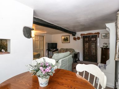 A living room with a wooden table and flower pot a sofa television and decorative wooden door at Small Piece in Porlock