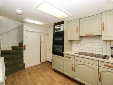 A kitchen with green carpeted stairs built in double oven microwave and tiled countertop at Small Piece in Porlock