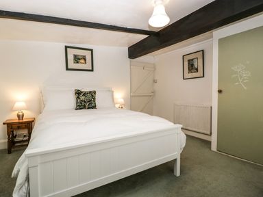 A bedroom with a white bed frame and bedside tables with lamps at Small Piece in Porlock
